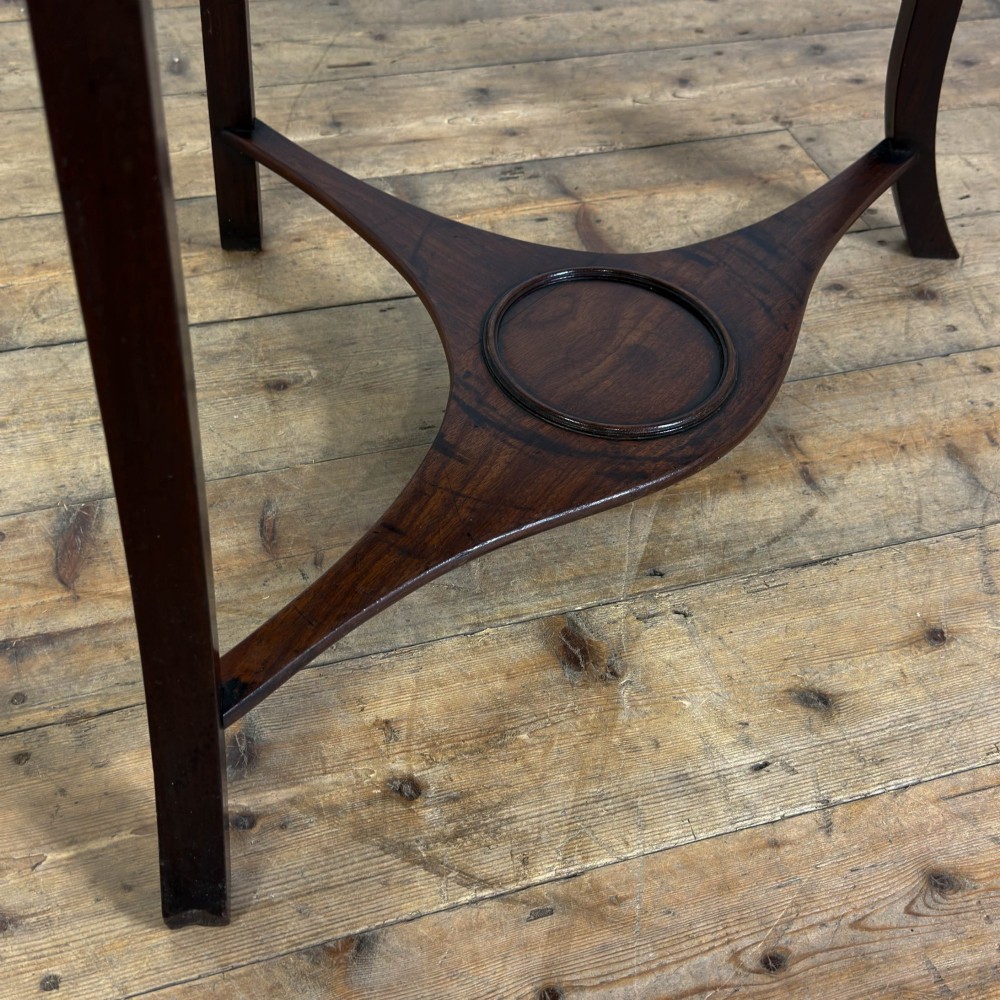 A Georgian dark mahogany triangular corner washstand featuring a smooth top shelf, a middle tier with three drawer fronts and brass ring handles, and slender legs connected by a lower stretcher. View VIII