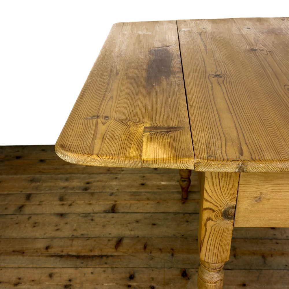 A pine drop leaf kitchen table featuring turned legs and hinged side panels that fold down. View II