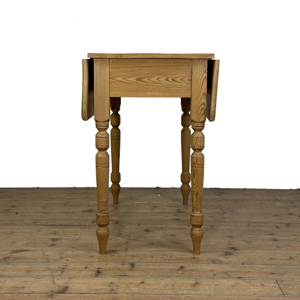A pine drop leaf kitchen table featuring turned legs and hinged side panels that fold down. View IV