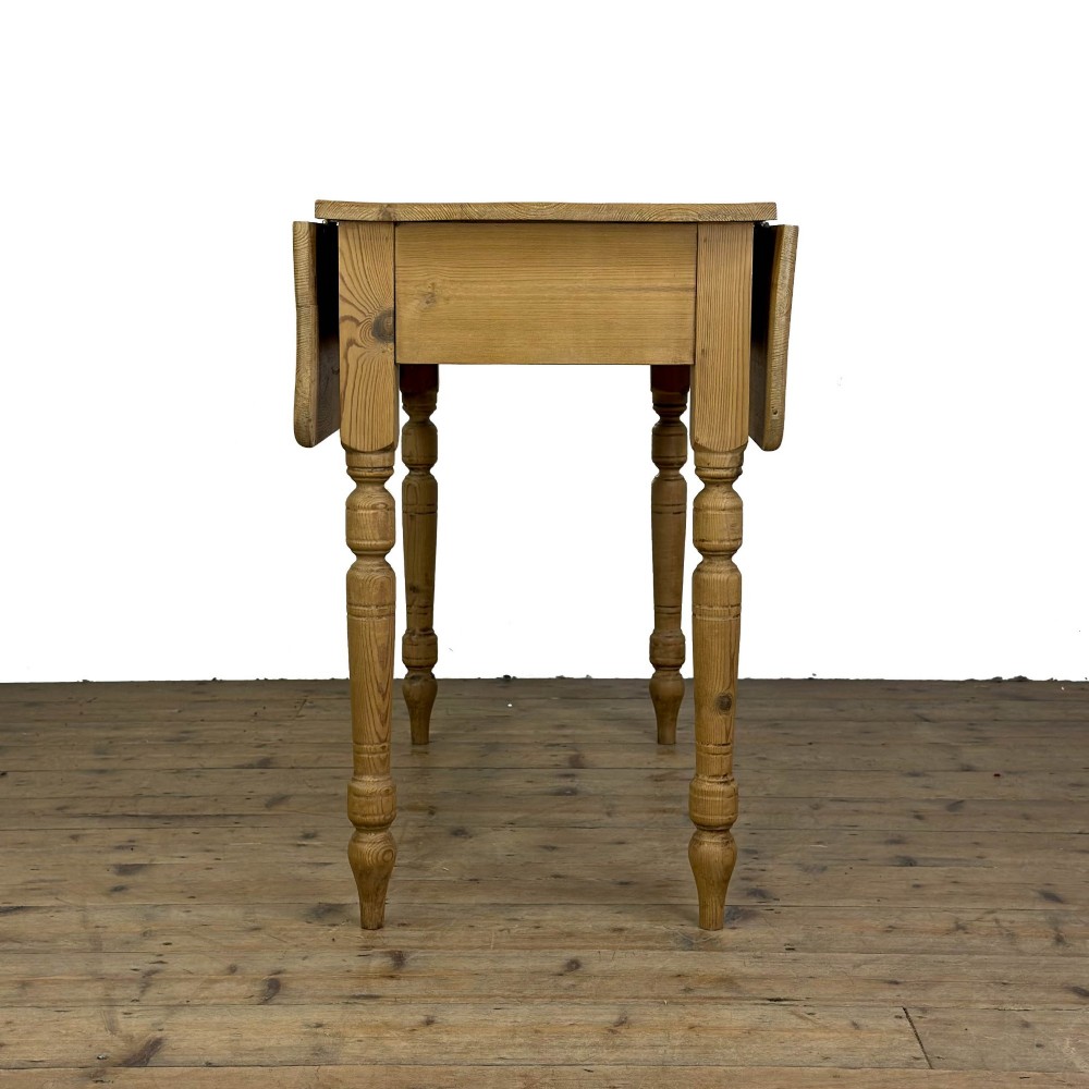 A pine drop leaf kitchen table featuring turned legs and hinged side panels that fold down. View VI