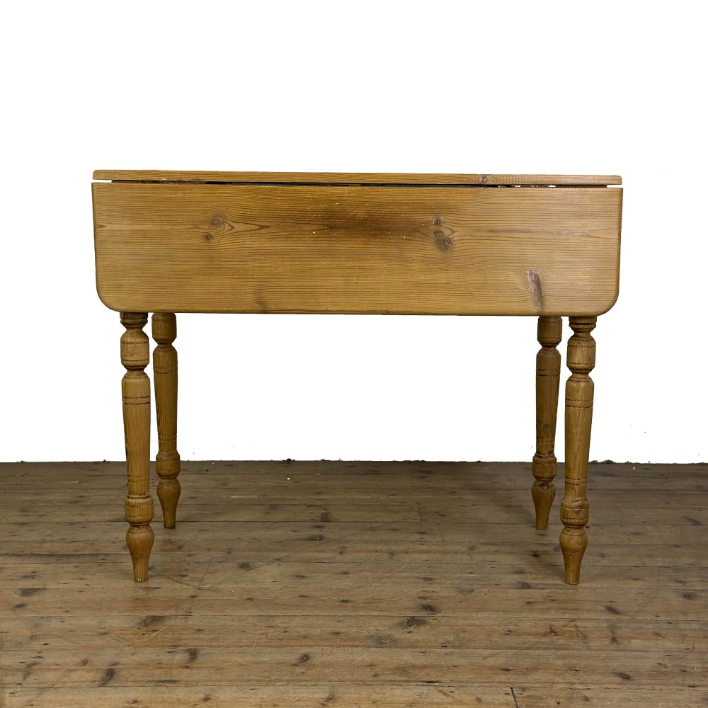 A pine drop leaf kitchen table featuring turned legs and hinged side panels that fold down. View VII