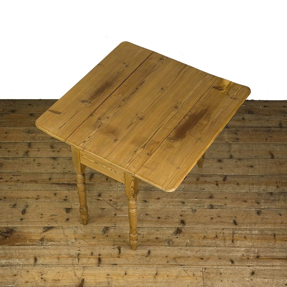 A pine drop leaf kitchen table featuring turned legs and hinged side panels that fold down. View IX