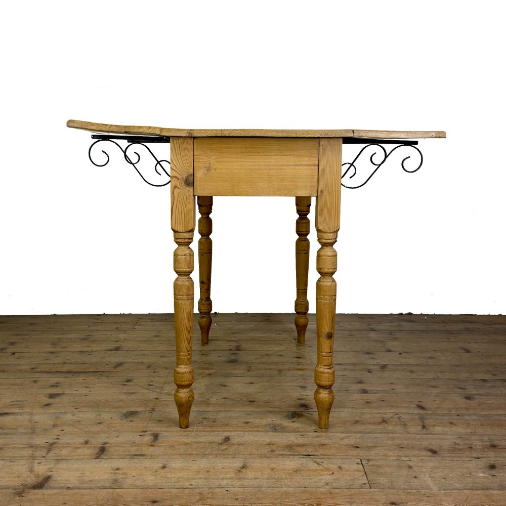 A pine drop leaf kitchen table featuring turned legs and hinged side panels that fold down. View XI