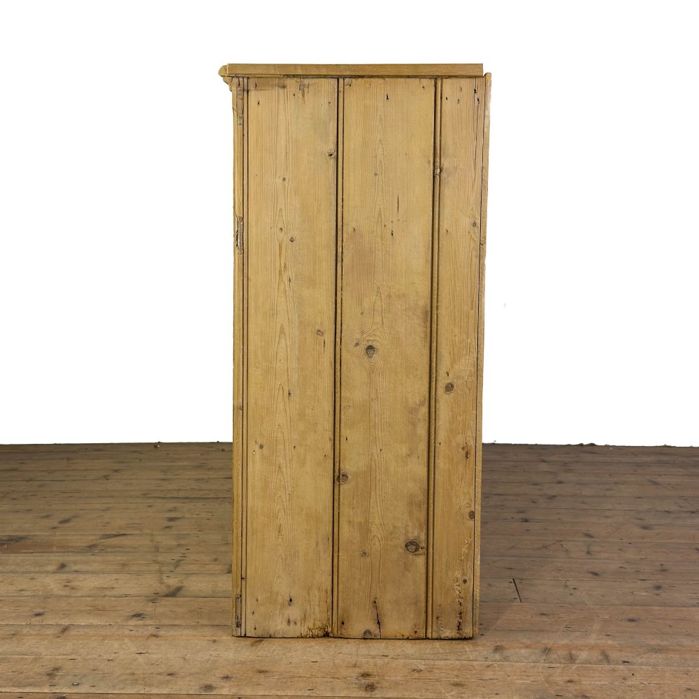 A Victorian pine dresser base with three frieze drawers, ceramic drawer knobs, two panelled cupboard doors, and a central open shelving recess. View VI