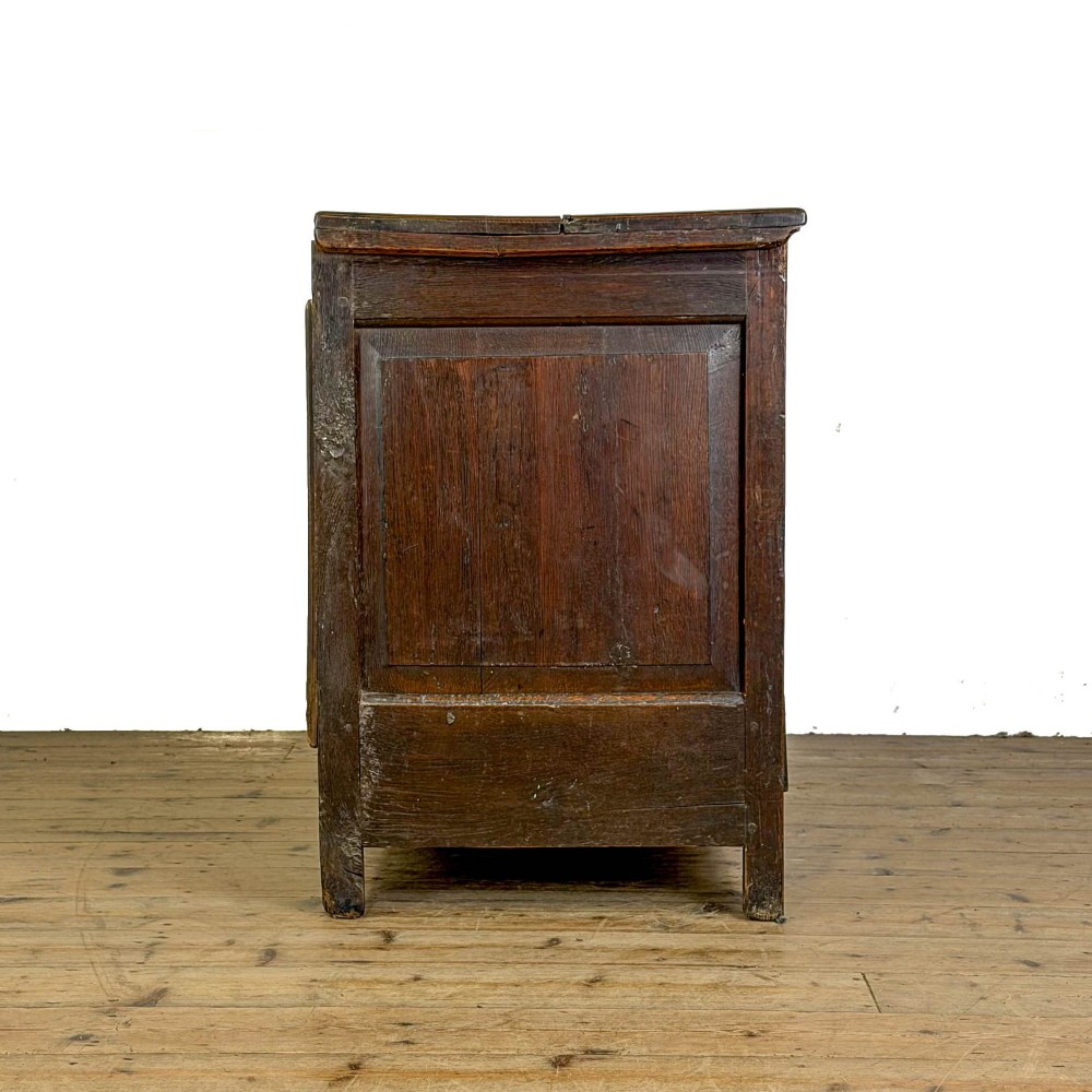 An 18th-century dark oak mule chest featuring three raised fielded panels, two lower drawers with brass swan-neck handles, and carved initial detailing. View X