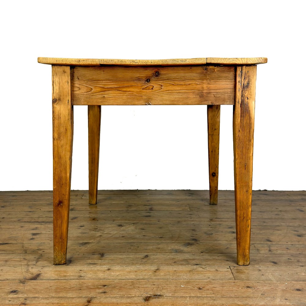 An antique pine kitchen table featuring a plank top, a single apron drawer with a cast iron cup handle, and four tapered square legs. View V