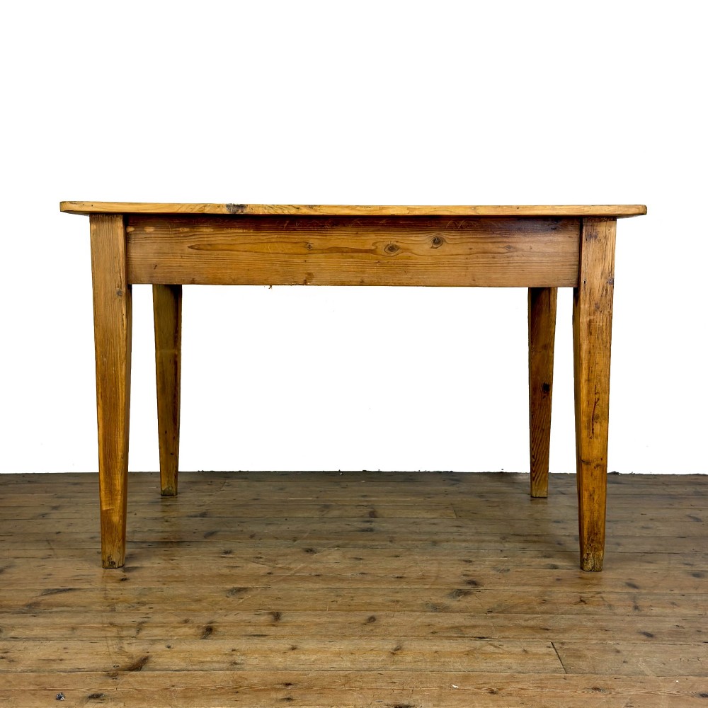 An antique pine kitchen table featuring a plank top, a single apron drawer with a cast iron cup handle, and four tapered square legs. View VI