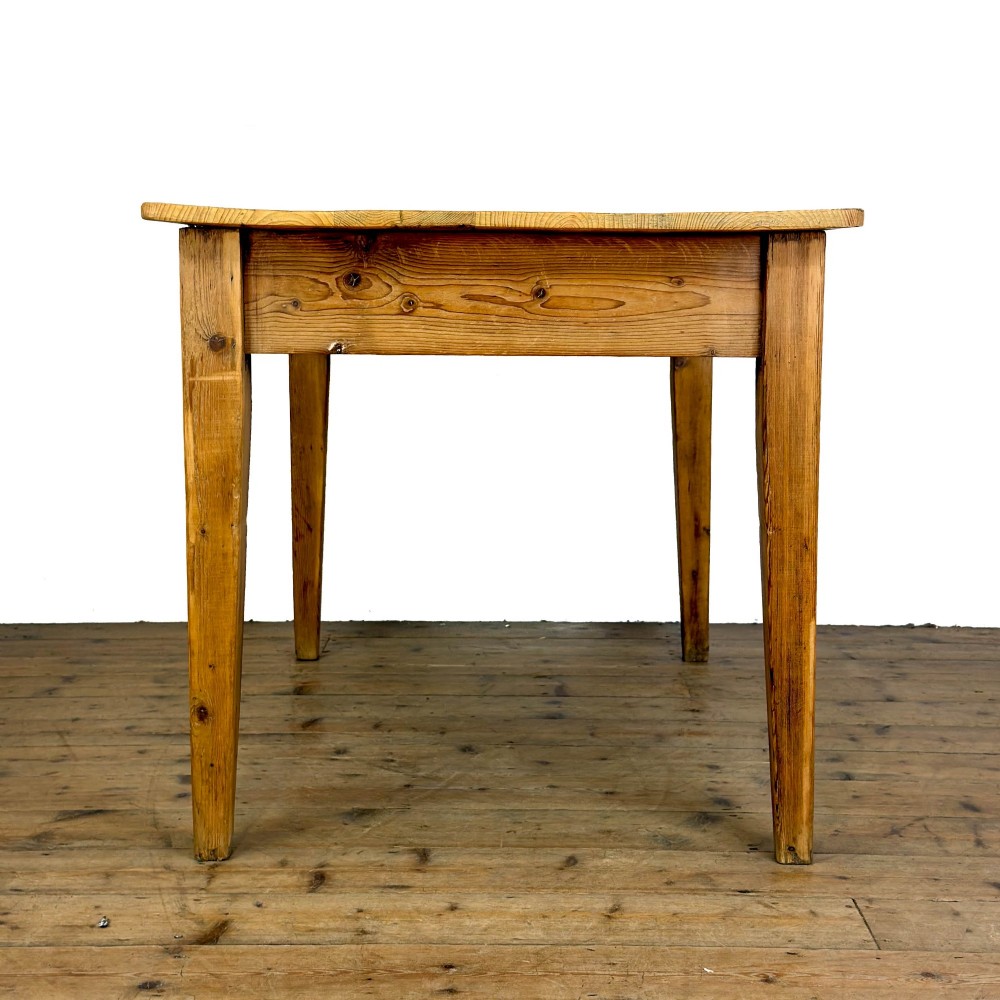 An antique pine kitchen table featuring a plank top, a single apron drawer with a cast iron cup handle, and four tapered square legs. View VII