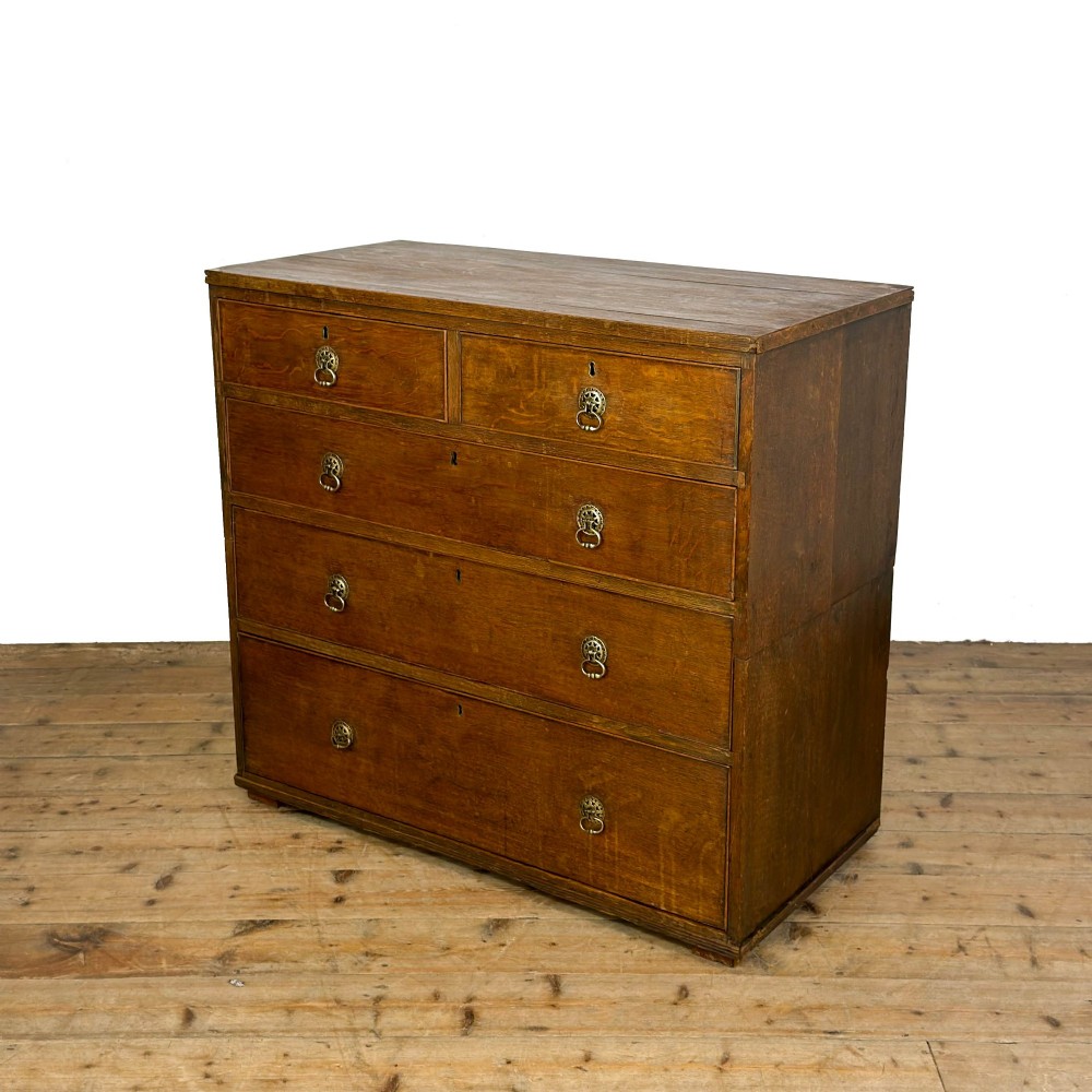 A nineteenth-century oak chest of drawers featuring two short over three long drawers with brass ring handles.