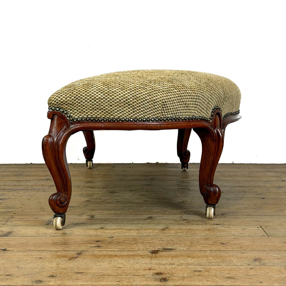 A long curved Victorian upholstered window seat featuring carved mahogany cabriole legs on castors and a patterned textile seat with studding detail. View V