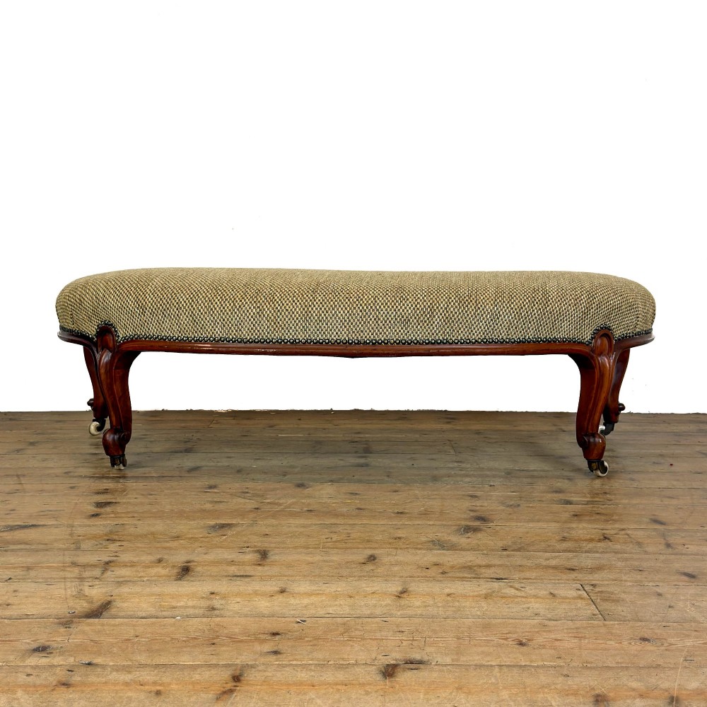A long curved Victorian upholstered window seat featuring carved mahogany cabriole legs on castors and a patterned textile seat with studding detail. View VI