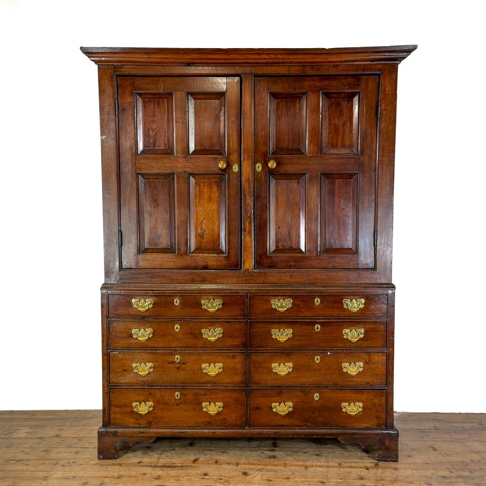 An eighteenth-century two-part Georgian oak livery cupboard with two multi-panelled doors above eight brass-handled drawers.