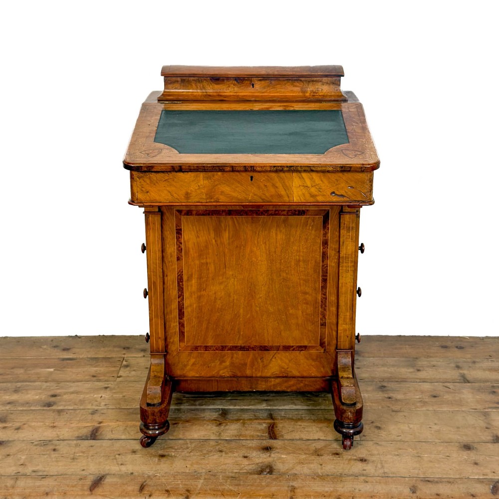 A Victorian burr walnut Davenport desk featuring a green leather writing slope, upper stationer compartment, side drawers, and brass castors.