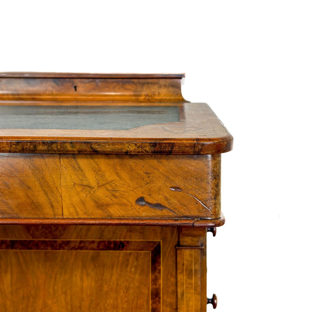 A Victorian burr walnut Davenport desk featuring a green leather writing slope, upper stationer compartment, side drawers, and brass castors. View IV