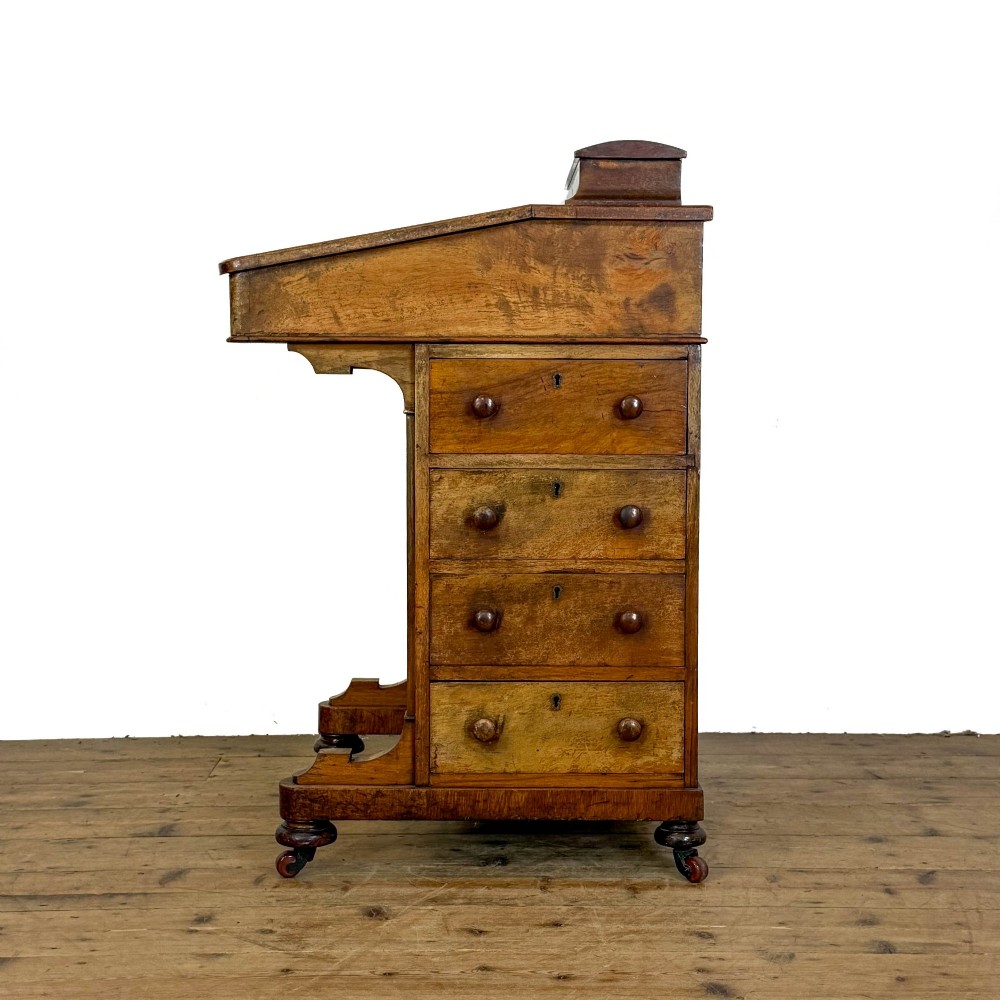 A Victorian burr walnut Davenport desk featuring a green leather writing slope, upper stationer compartment, side drawers, and brass castors. View X