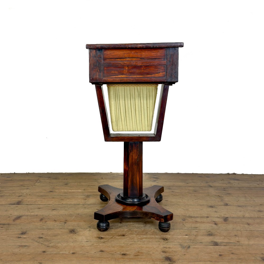 A 19th-century rosewood work table featuring small drawers, a pleated cream fabric basket underneath, a central pedestal support, and a quadruped base. View VIII