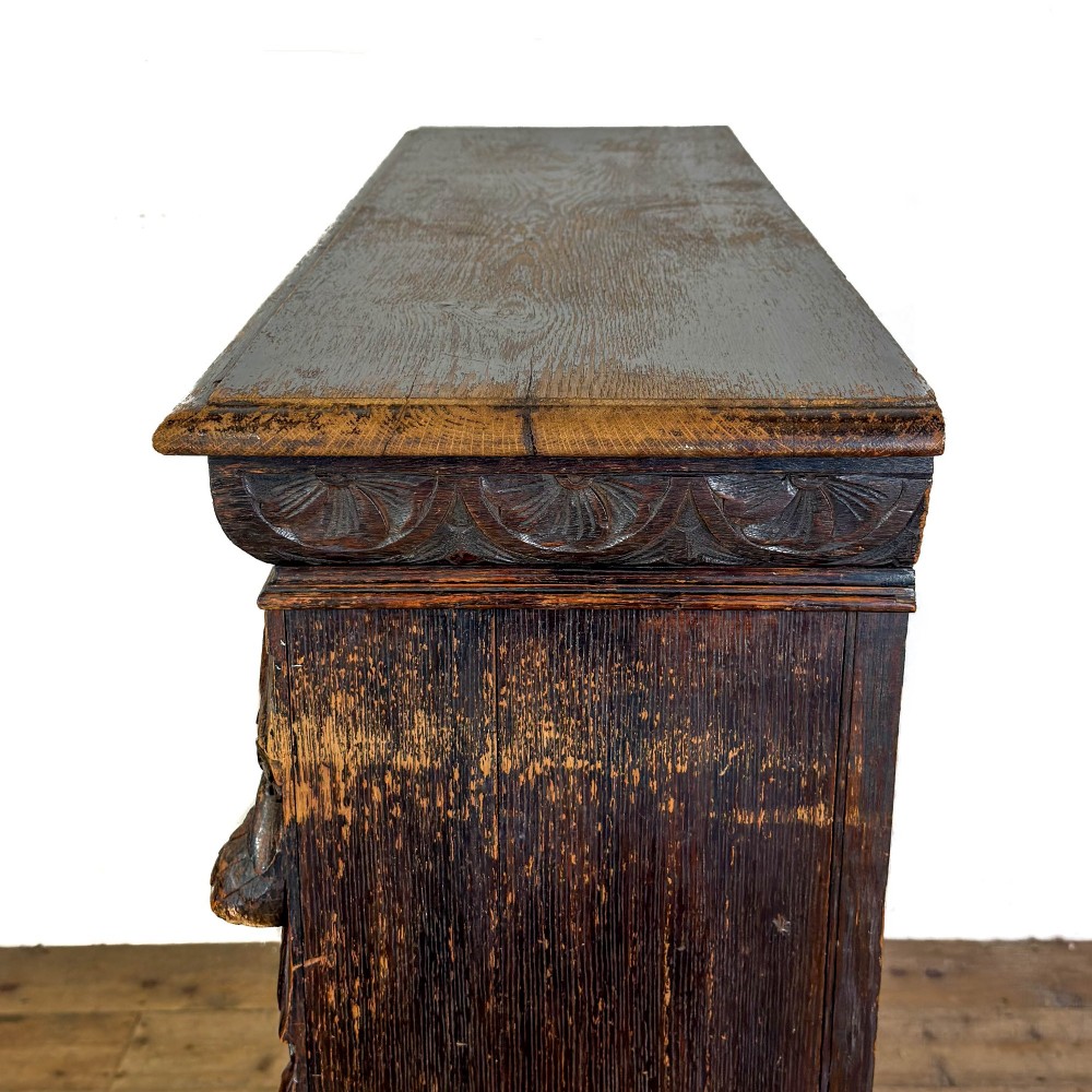 An antique dark oak open bookcase featuring hand-carved foliate detailing along the stiles and a carved upper frieze. View V
