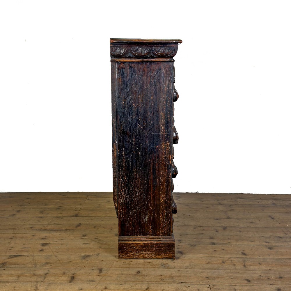 An antique dark oak open bookcase featuring hand-carved foliate detailing along the stiles and a carved upper frieze. View VII