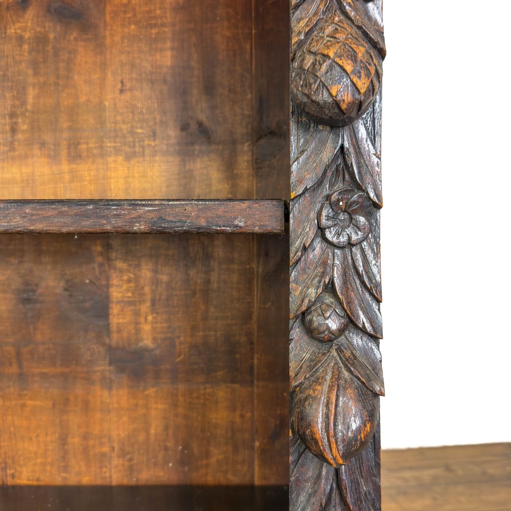 An antique dark oak open bookcase featuring hand-carved foliate detailing along the stiles and a carved upper frieze. View X