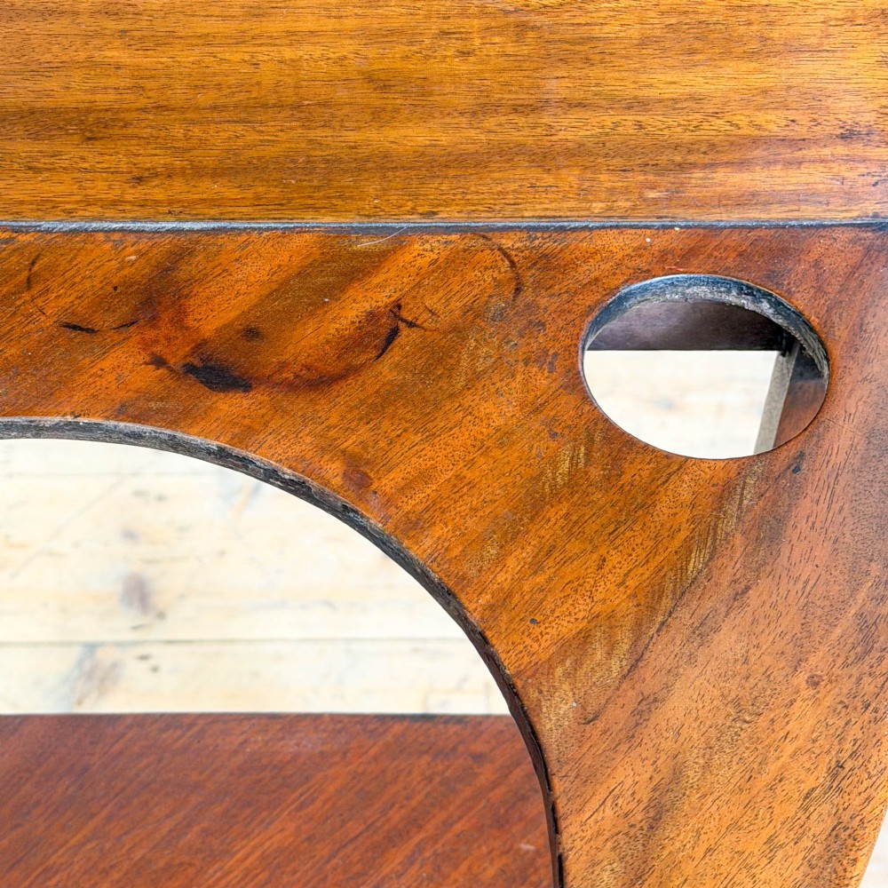 An antique mahogany corner washstand featuring a curved splashback, top circular basin cut-outs, a central drawer, and splayed legs connected by a lower stretcher shelf. View IX