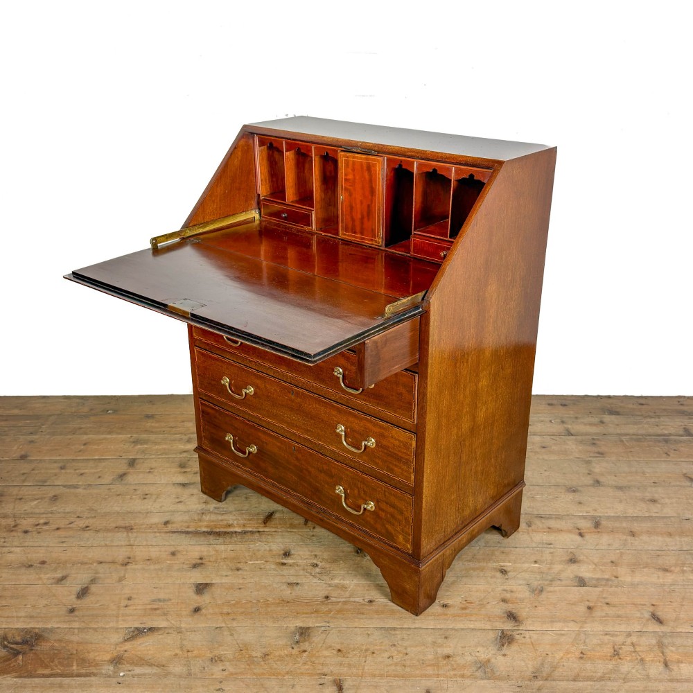 An antique Edwardian mahogany writing bureau featuring a sloping fall-front top with a shell marquetry inlay, situated above four graduating drawers with brass handles on bracket feet. View V