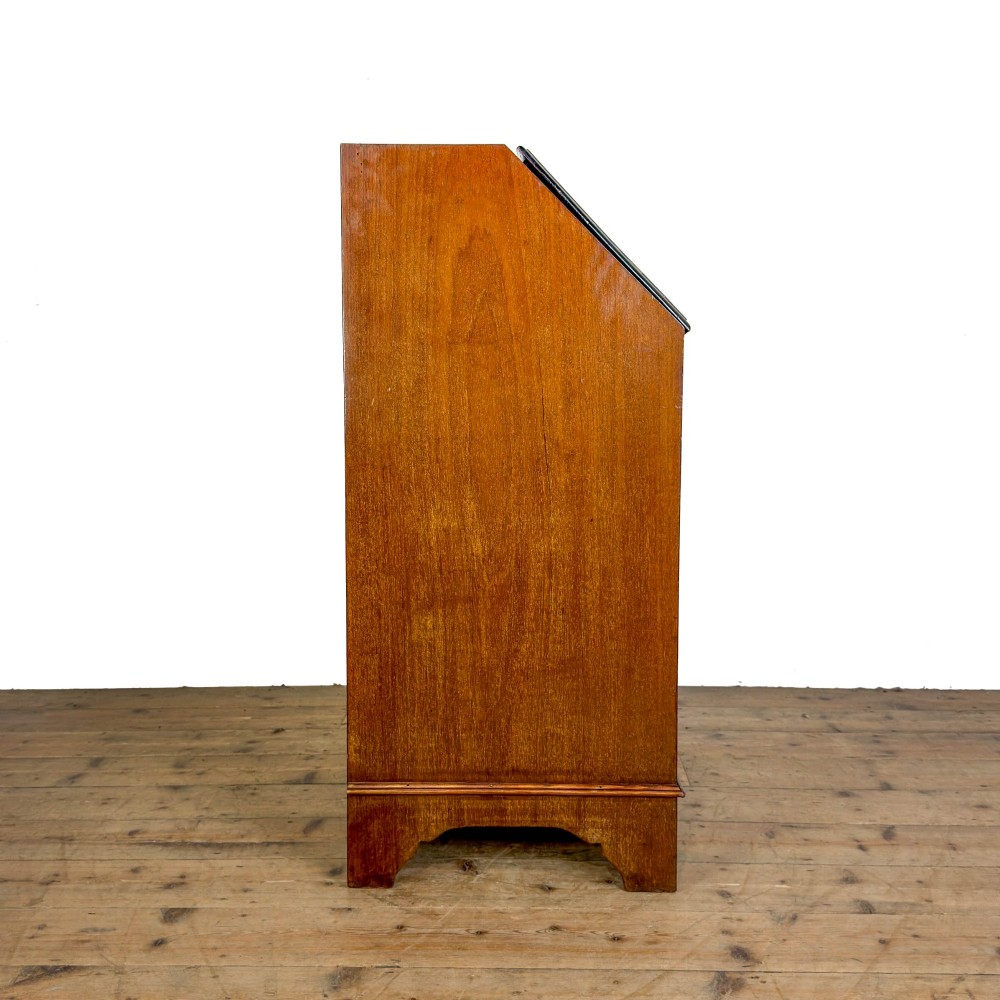 An antique Edwardian mahogany writing bureau featuring a sloping fall-front top with a shell marquetry inlay, situated above four graduating drawers with brass handles on bracket feet. View VIII