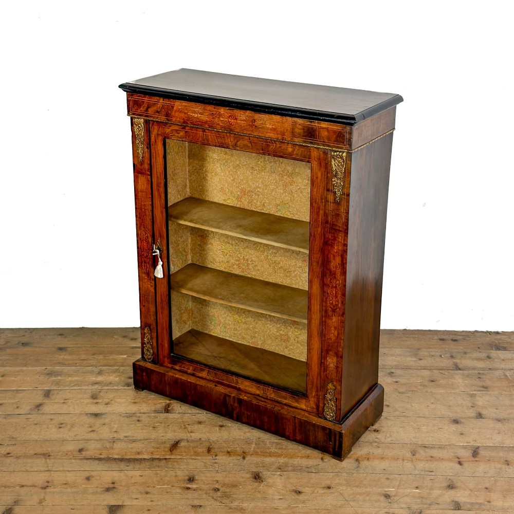 A Victorian inlaid walnut pier cabinet featuring a single glazed door, ormolu brass mounts, floral interior lining, and two interior shelves. View II