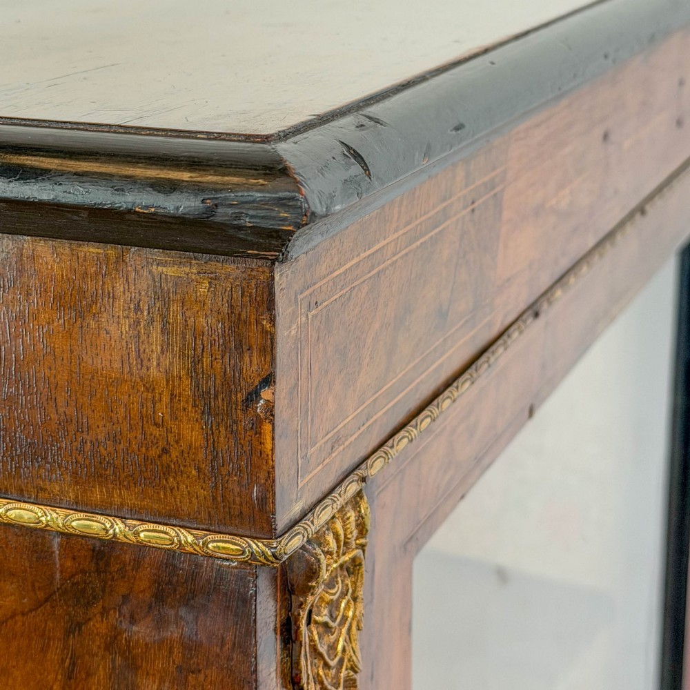 A Victorian inlaid walnut pier cabinet featuring a single glazed door, ormolu brass mounts, floral interior lining, and two interior shelves. View VI