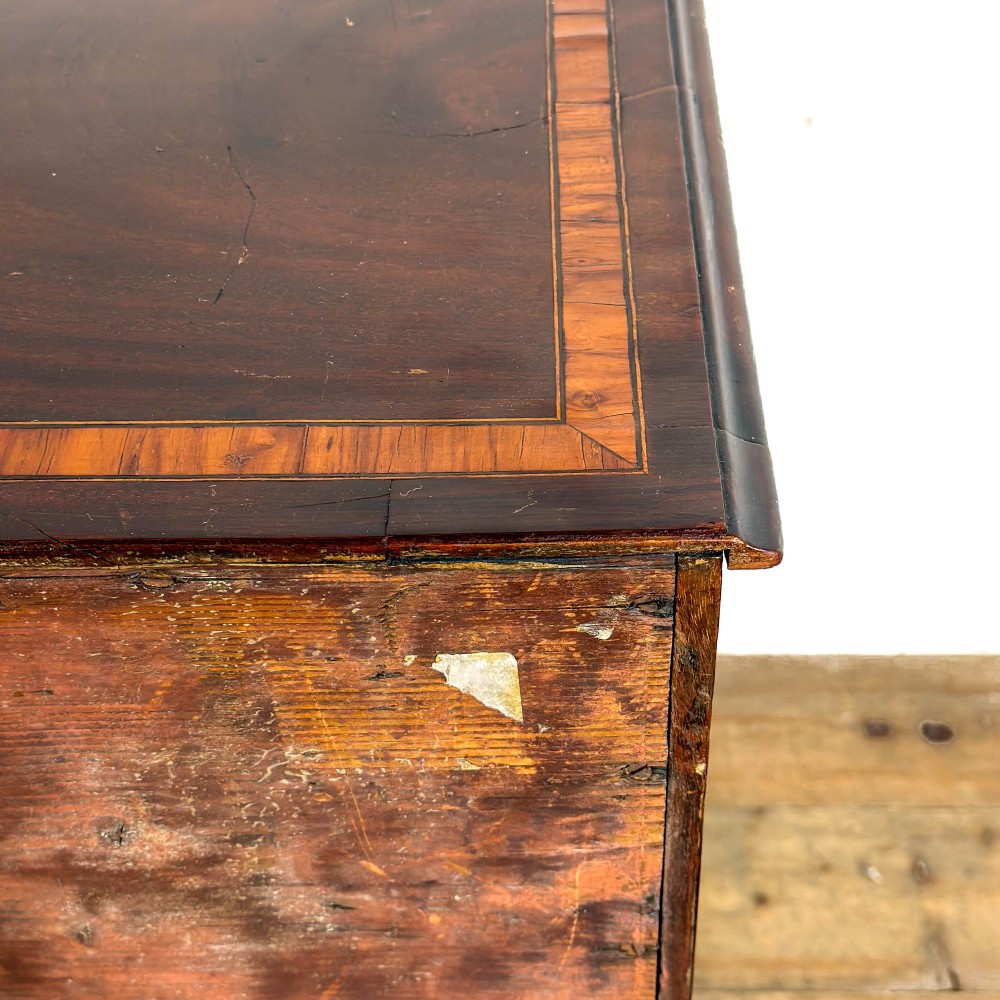 An antique mahogany bachelors chest featuring four crossbanded graduated drawers with brass handles, a brushing slide, and bracket feet. View VII
