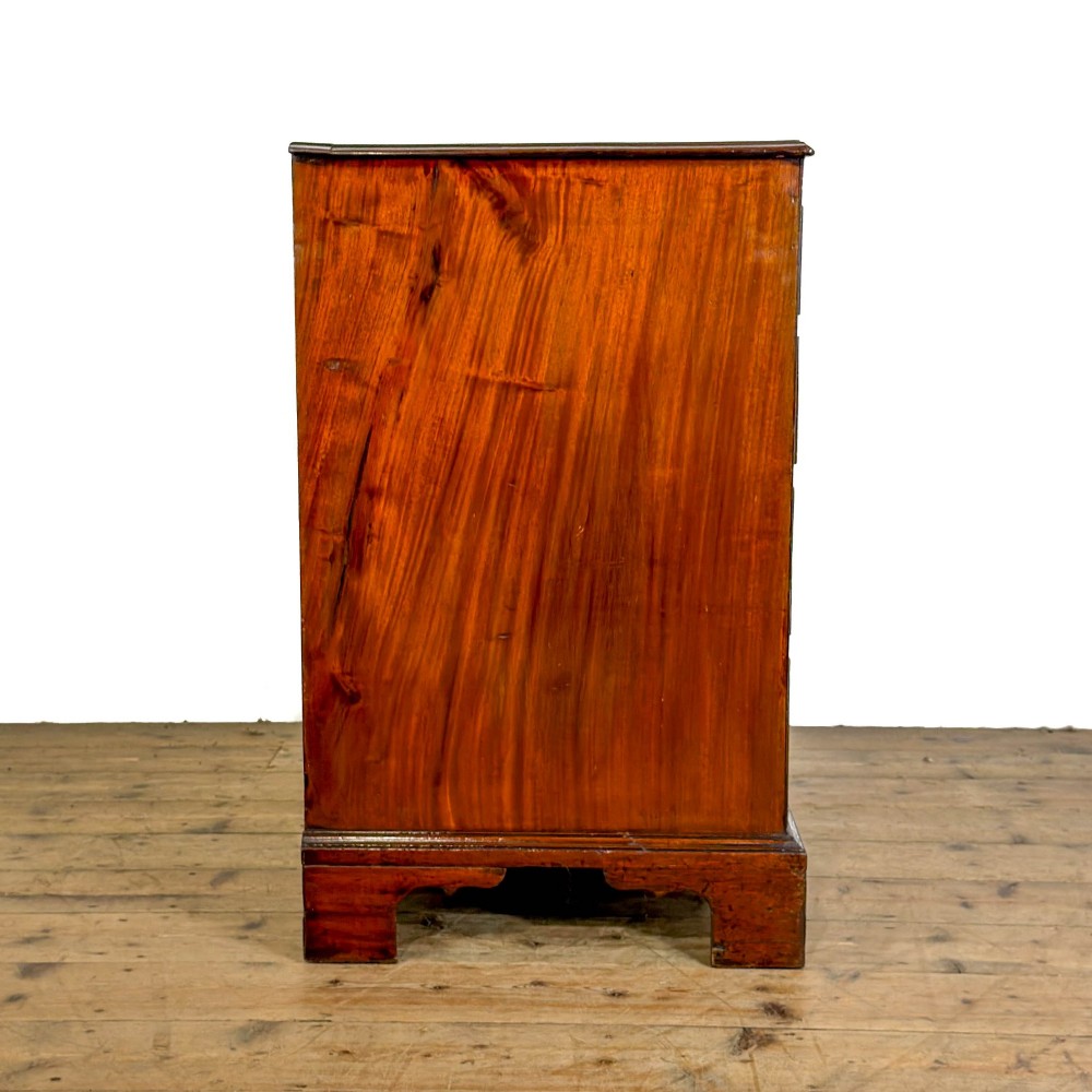 An antique mahogany bachelors chest featuring four crossbanded graduated drawers with brass handles, a brushing slide, and bracket feet. View VIII