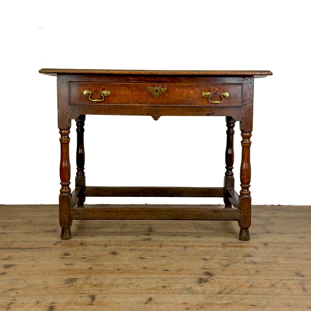 An 18th-century oak lowboy side table featuring a single drawer with brass drop handles, turned legs, and a lower box stretcher.