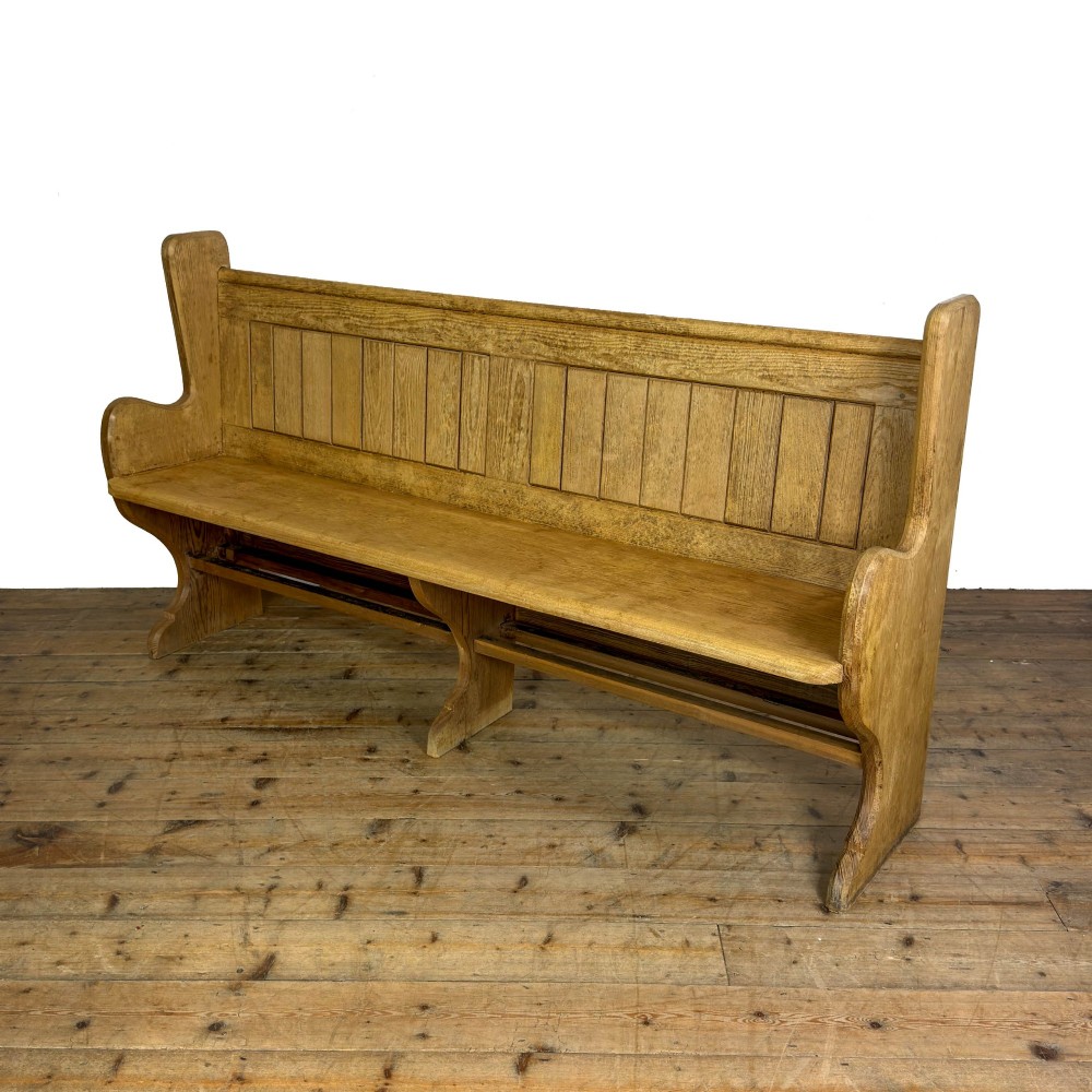 An antique pine chapel pew featuring a panelled backrest, integrated under-seat storage shelf, and sculpted bench ends. View II