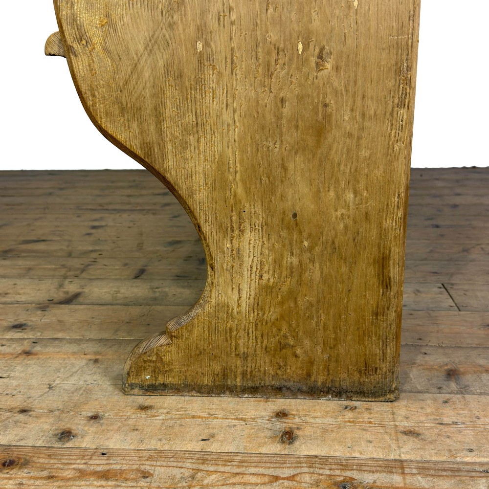 An antique pine chapel pew featuring a panelled backrest, integrated under-seat storage shelf, and sculpted bench ends. View V