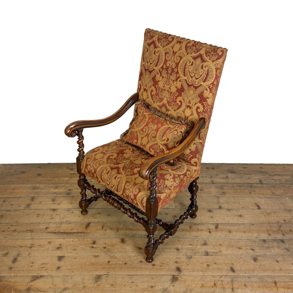An antique walnut elbow chair featuring barley twist turnings, scrolled arms, and red and gold patterned upholstery with a matching cushion. View VI