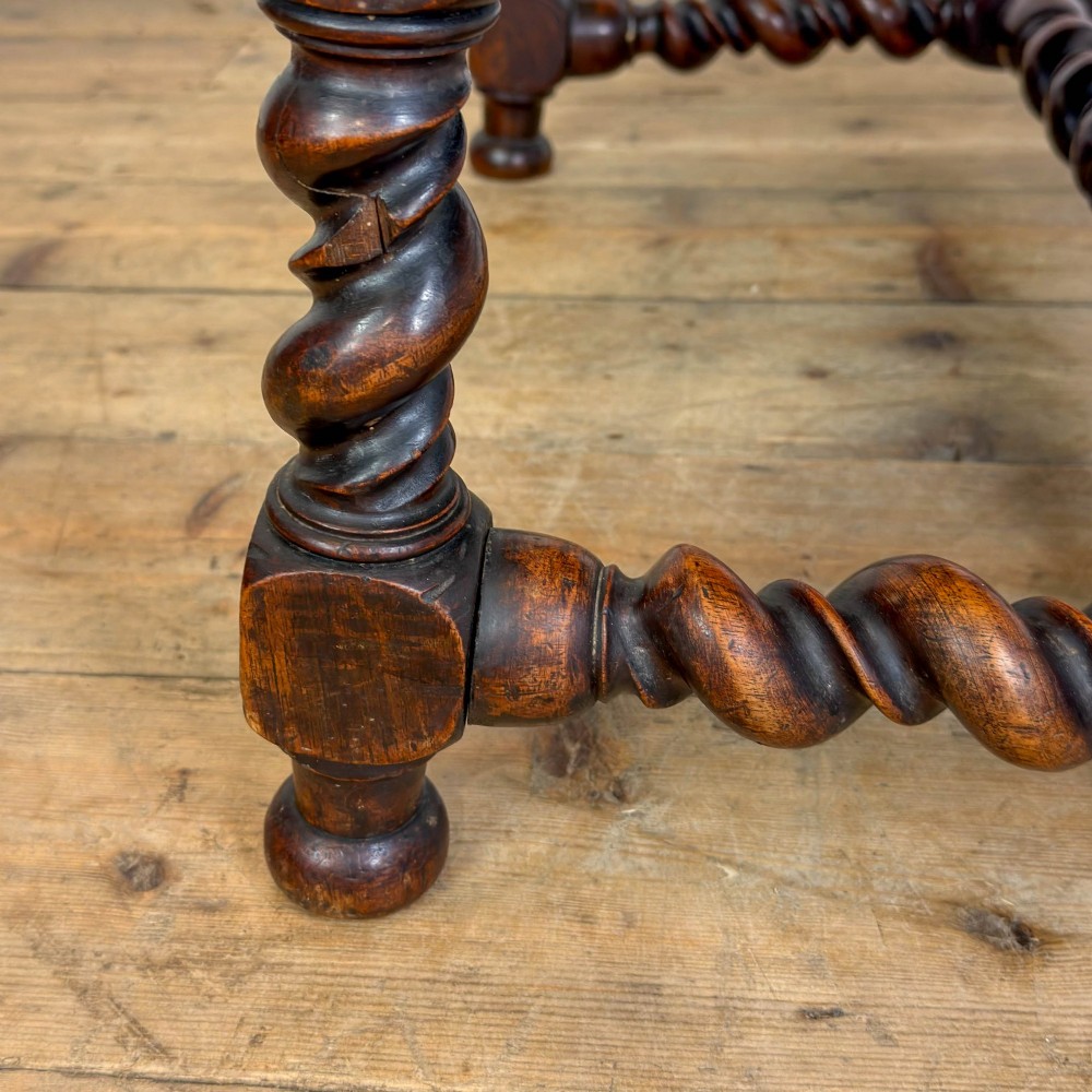 An antique walnut elbow chair featuring barley twist turnings, scrolled arms, and red and gold patterned upholstery with a matching cushion. View VII