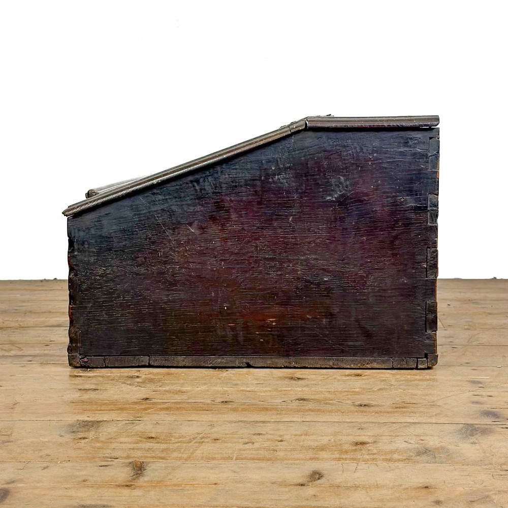 A dark brown oak bible box featuring a sloped hinged lid with a wooden rest ledge and an iron lockplate. View VII