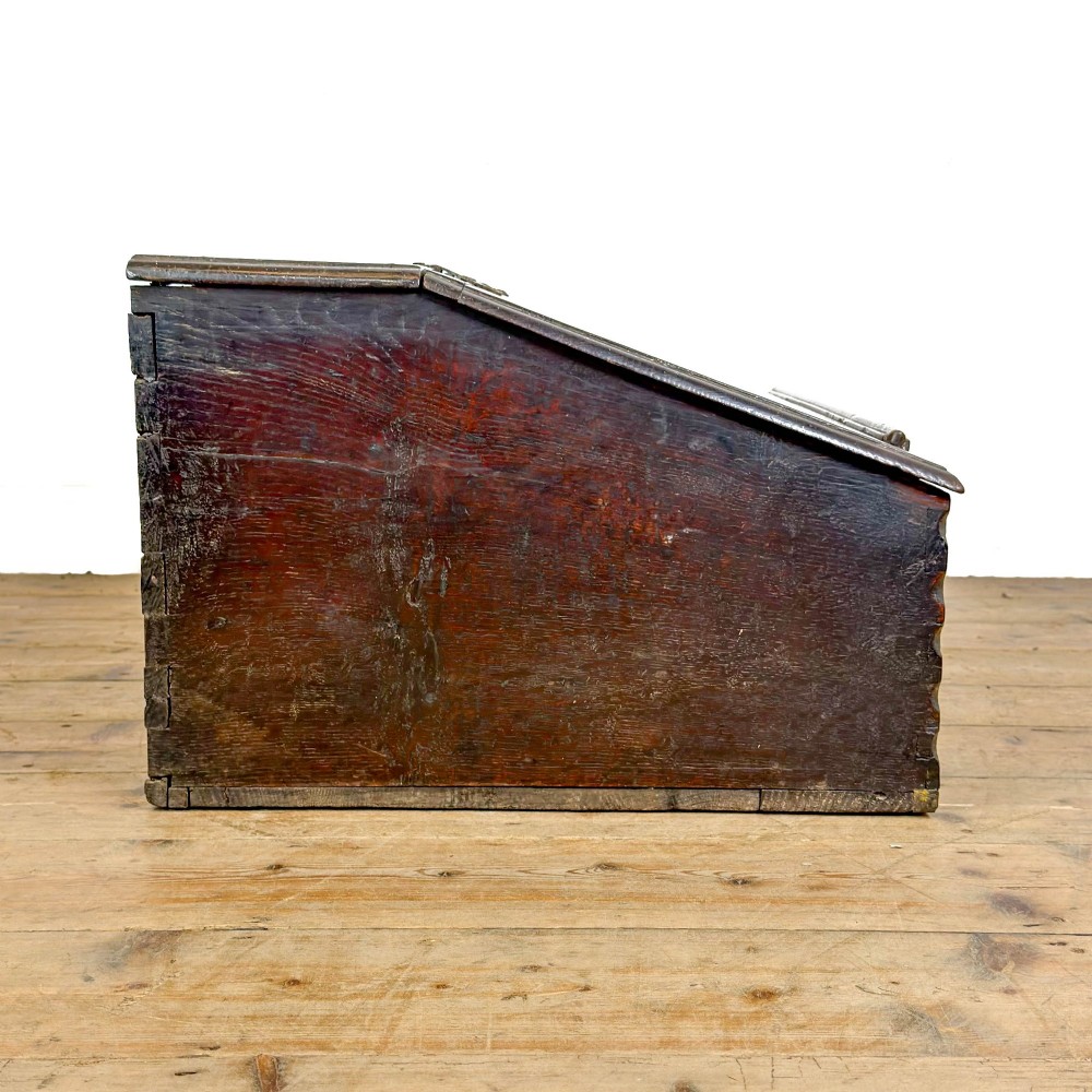 A dark brown oak bible box featuring a sloped hinged lid with a wooden rest ledge and an iron lockplate. View X
