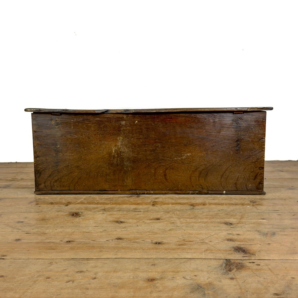 An 18th-century dark oak bible box featuring a hinged top lid, carved initials flanking a central iron lock plate, and a rectangular timber body. View V