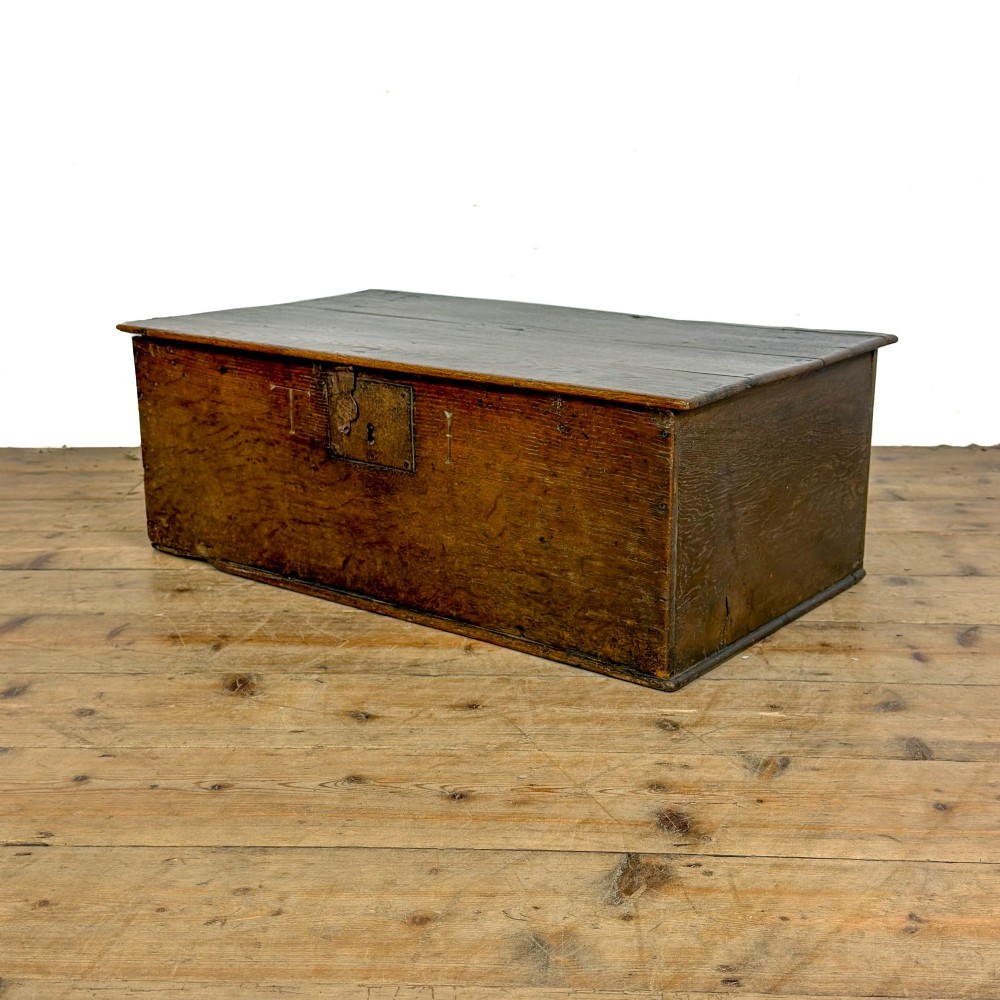 An 18th-century dark oak bible box featuring a hinged top lid, carved initials flanking a central iron lock plate, and a rectangular timber body. View VIII