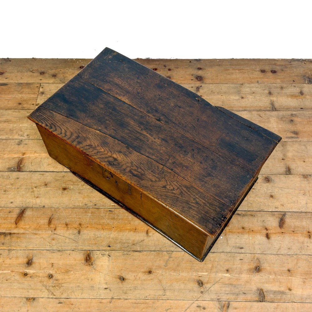 An 18th-century dark oak bible box featuring a hinged top lid, carved initials flanking a central iron lock plate, and a rectangular timber body. View IX