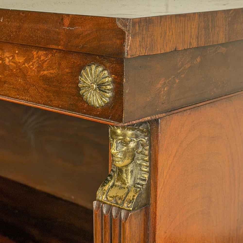 An antique Egyptian Revival mahogany open bookcase featuring fluted pilasters topped with cast brass sphinx heads, adjustable wooden shelves, and a plinth base. View IV