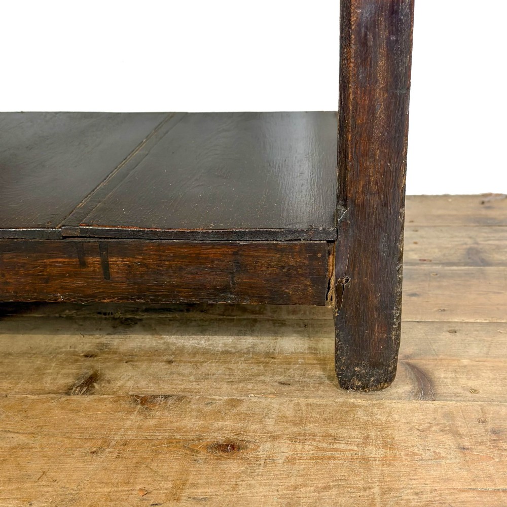A 19th-century dark oak dresser base featuring three upper drawers with brass oval handles, three decorative arched aprons, and a low potboard shelf. View V
