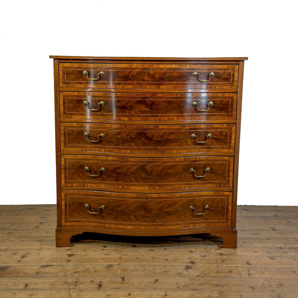 An antique mahogany serpentine chest featuring five graduated drawers with brass swan-neck handles and crossbanded inlay.