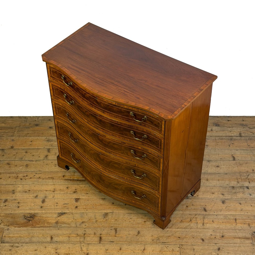 An antique mahogany serpentine chest featuring five graduated drawers with brass swan-neck handles and crossbanded inlay. View II