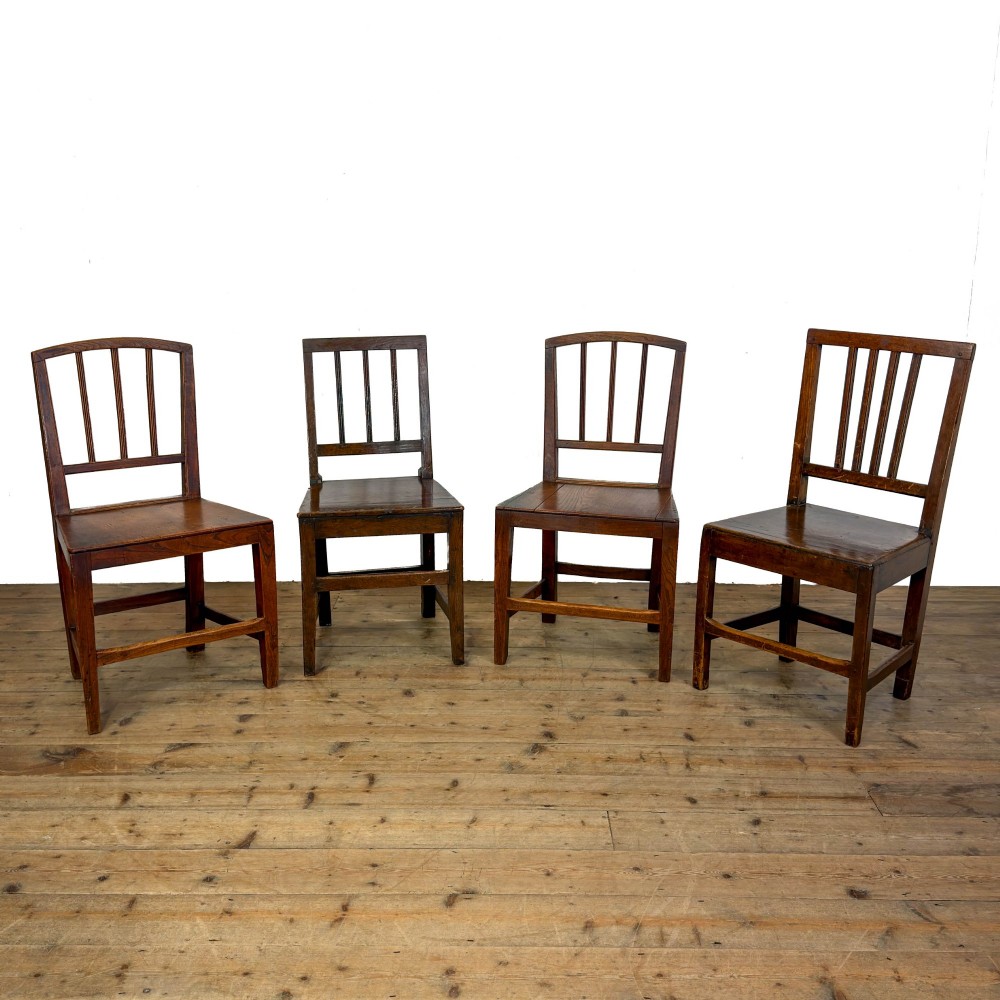 A set of four dark oak dining chairs with vertical slat backrests, solid timber seats, and straight square legs joined by stretchers.