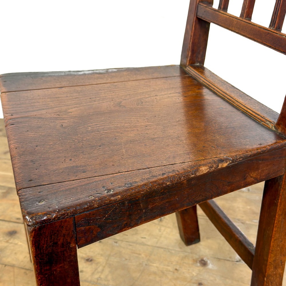 A set of four dark oak dining chairs with vertical slat backrests, solid timber seats, and straight square legs joined by stretchers. View III