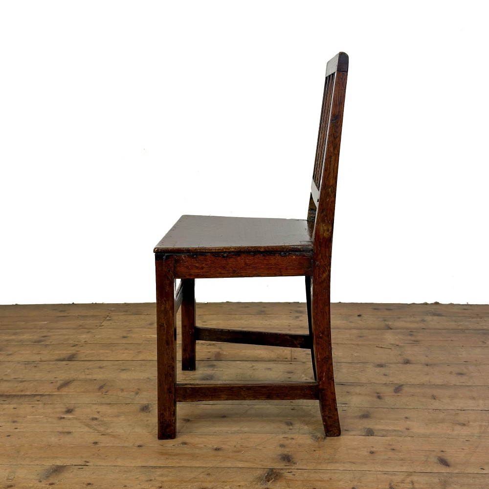A set of four dark oak dining chairs with vertical slat backrests, solid timber seats, and straight square legs joined by stretchers. View IX