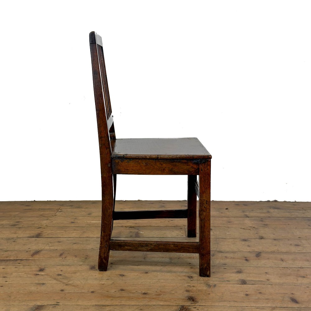 A set of four dark oak dining chairs with vertical slat backrests, solid timber seats, and straight square legs joined by stretchers. View XI