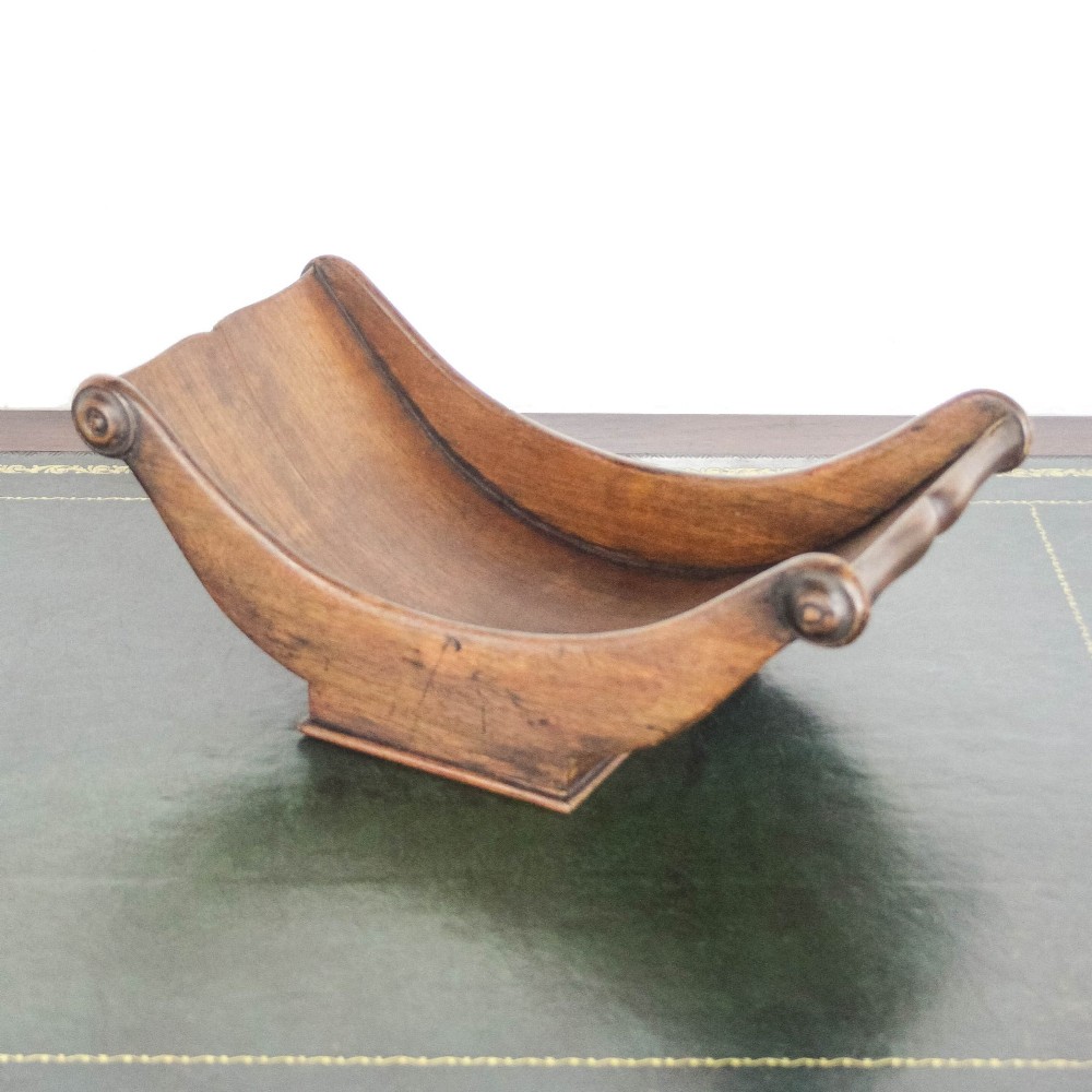 A Georgian mahogany cheese coaster featuring a curved trough with turned scroll ends resting on a rectangular base. View II