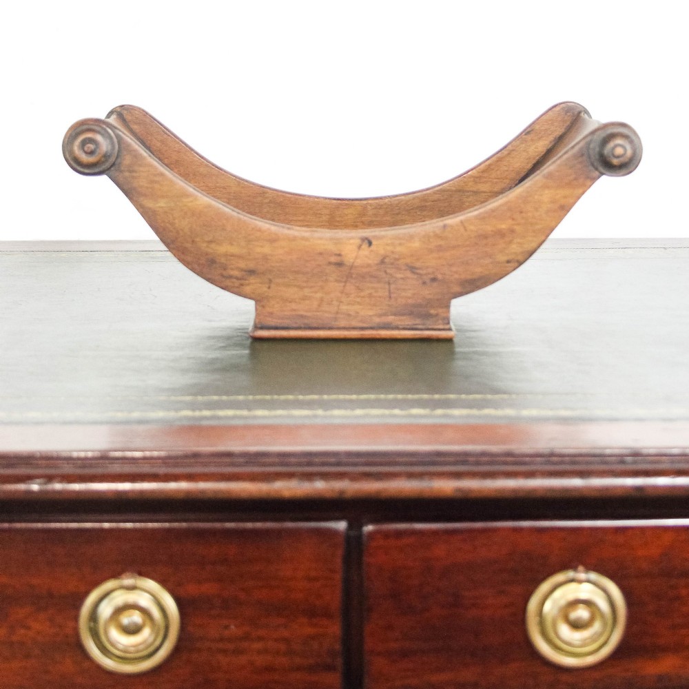 A Georgian mahogany cheese coaster featuring a curved trough with turned scroll ends resting on a rectangular base. View III